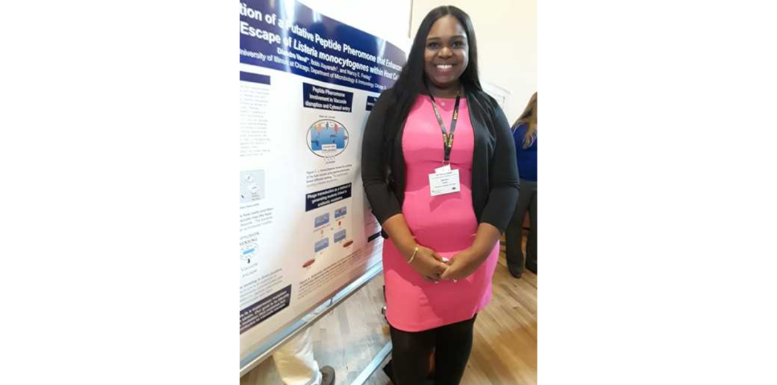 Diandra Vaval Taylor standing proud and smiling next to her conference poster