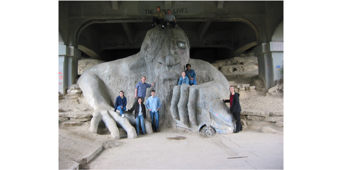 People posing for picture in front of a giant sculpture of a monster with 