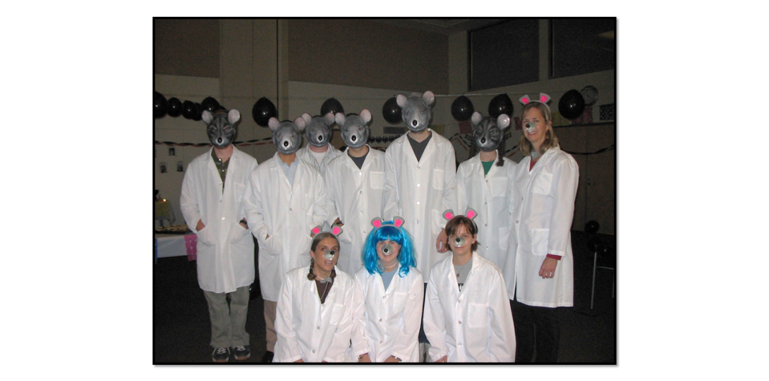 Group of scientists in white coats and wearing masks of mice and rats, posing for a picture