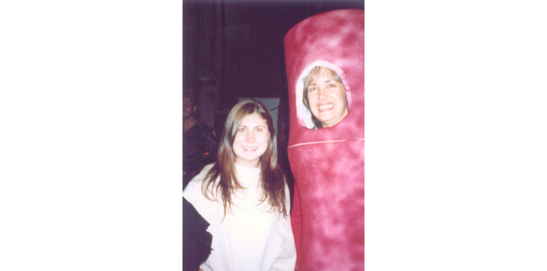 A young woman posing for a picture with Nancy wearing a costume of bacteria or sausage