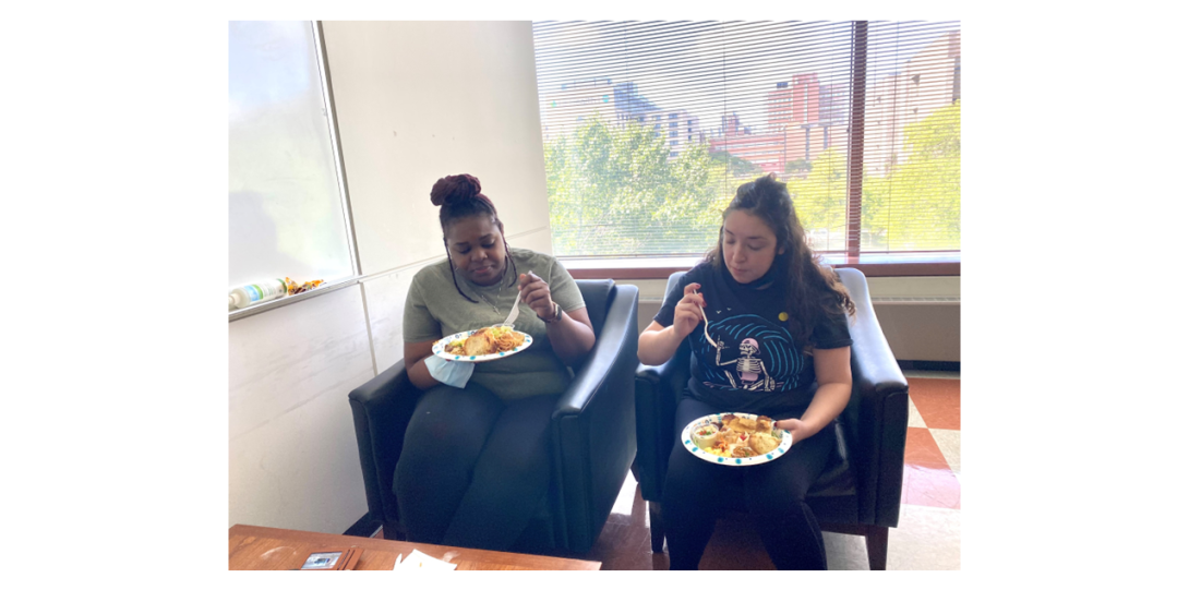 Diandra Taylor and Andrea Ochoa-Raya sitting in the armchairs and deeply focused on eating food