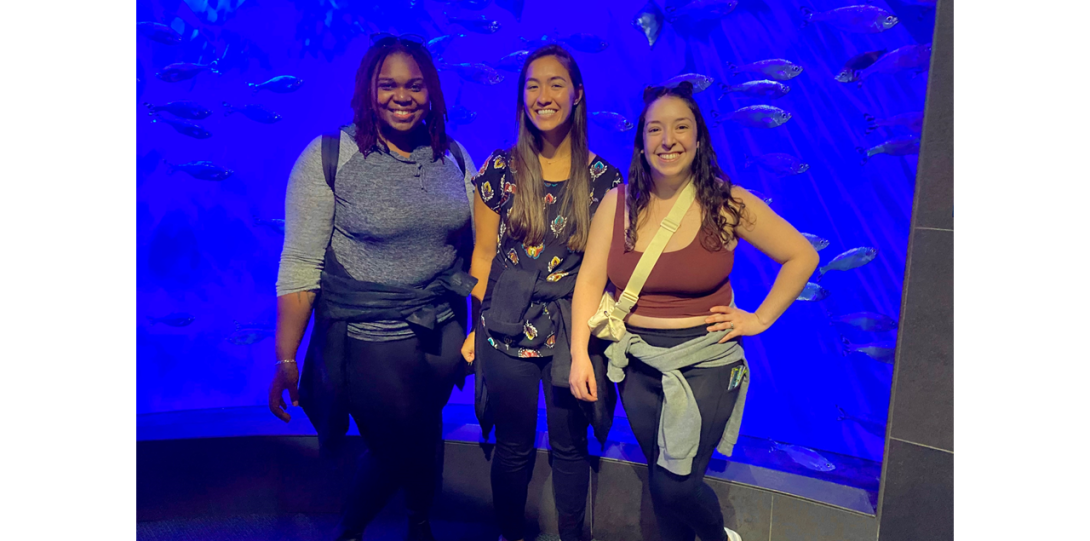 Diandra Taylor, Dee Dee Keen, and Andrea Ochoa-Raya posing in front of a large aquarium.