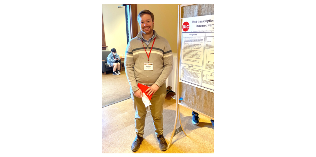 Sam Eallonardo standing next to his poster, with a red notebook in his hand